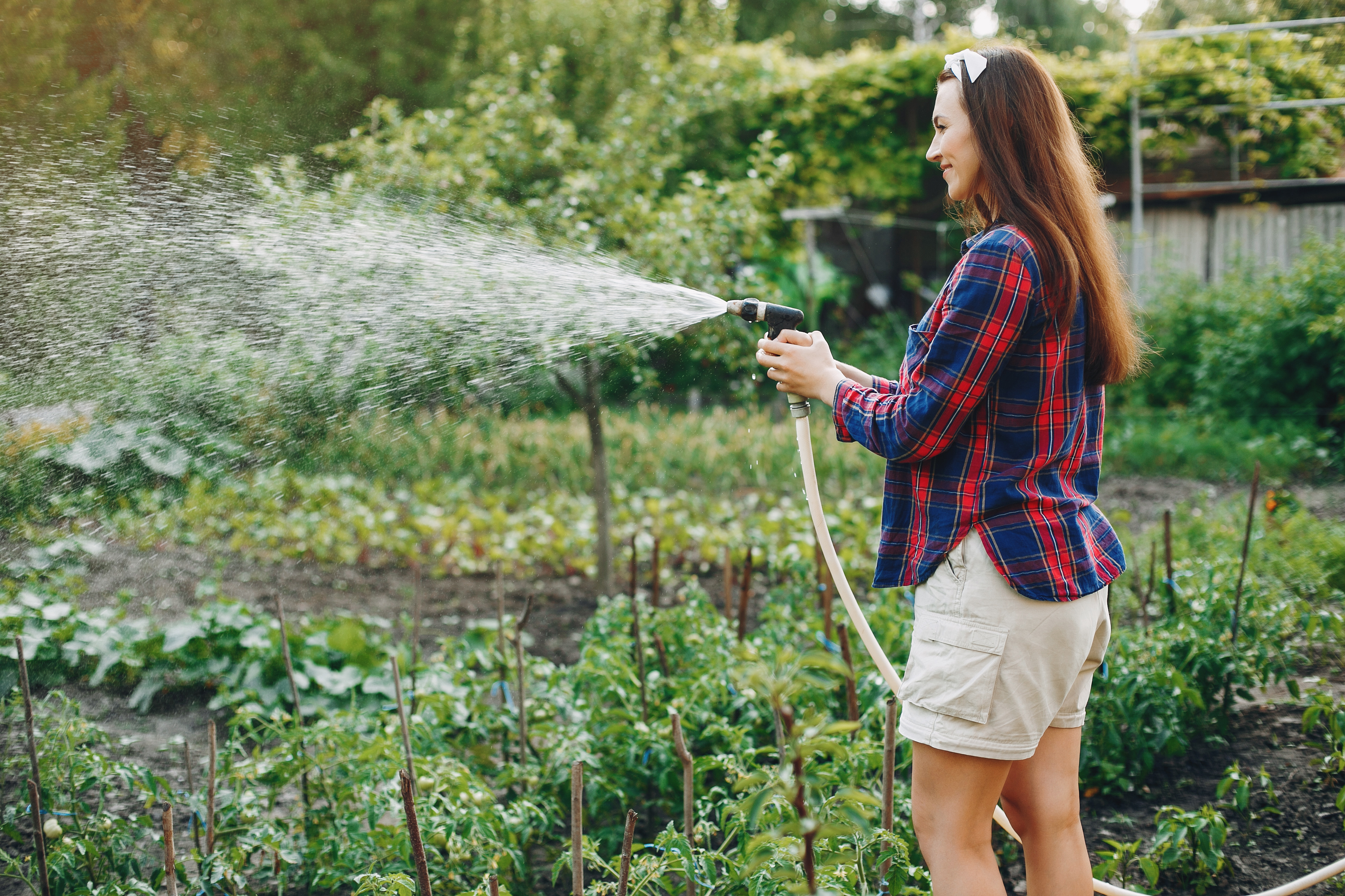 Beautiful woman works in a garden near the house